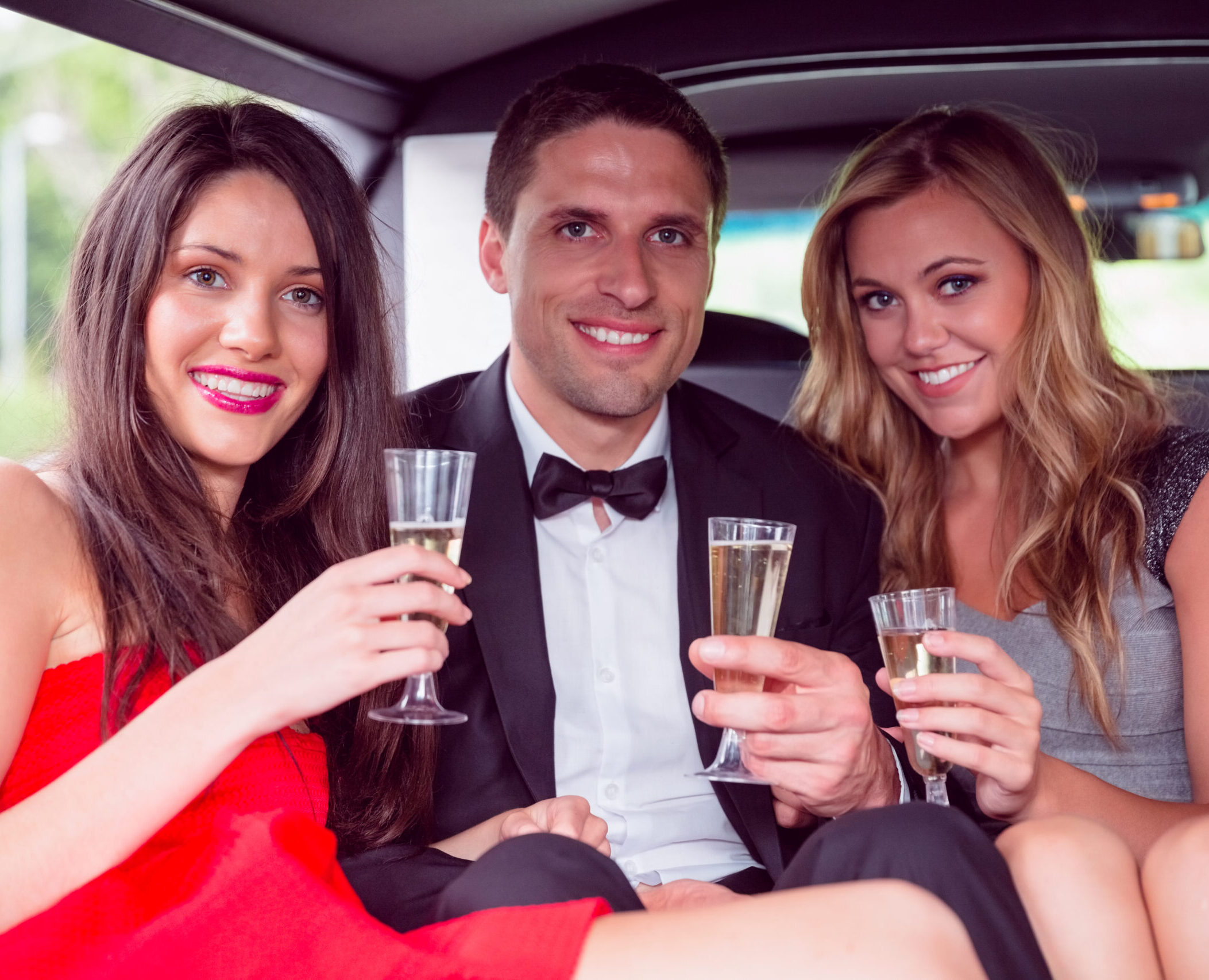 Happy friends drinking champagne in limousine on a night out